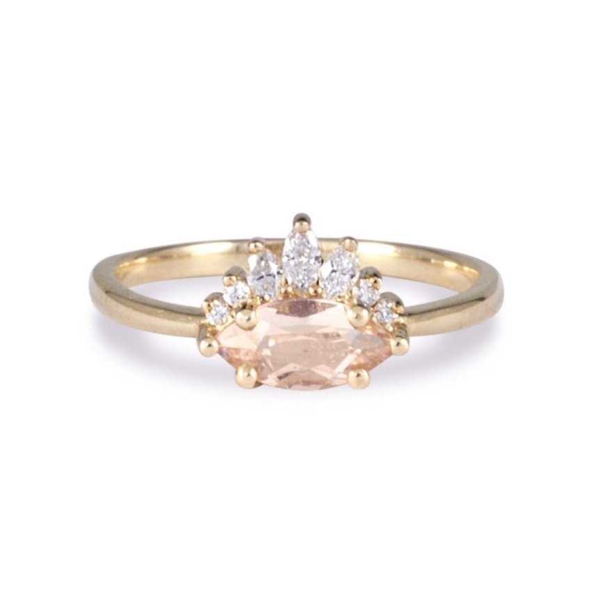 Marquise morganite ring with white diamond ground on yellow gold band close up on white background.