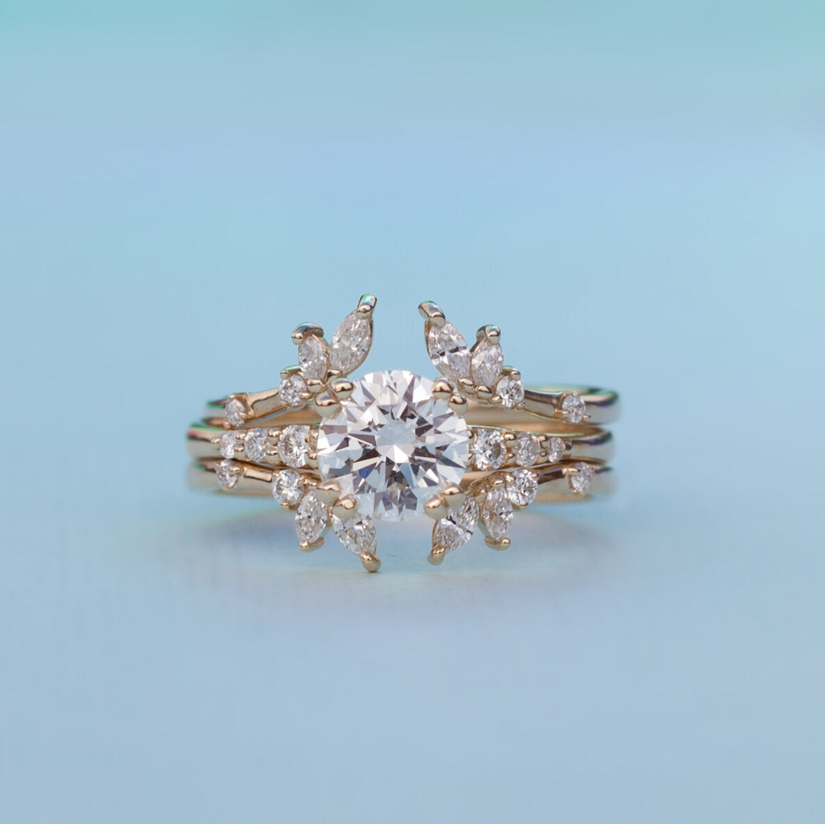 Load image into Gallery viewer, Diamond solitaire Rheia ring stacked with two white diamond bands on light blue background.
