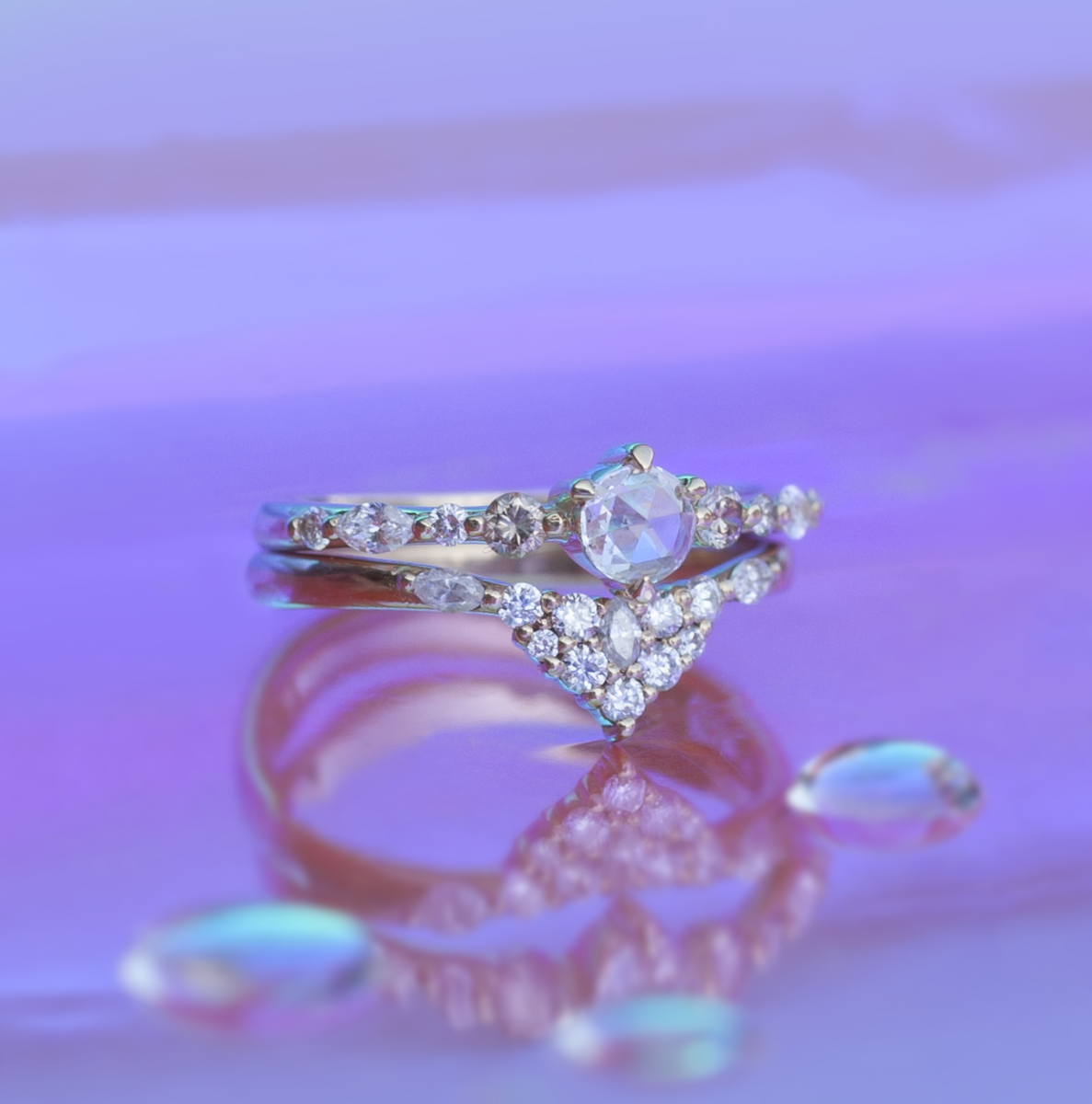 Diamond solitaire spirit dust ring stacked with a diamond band on multi color background.