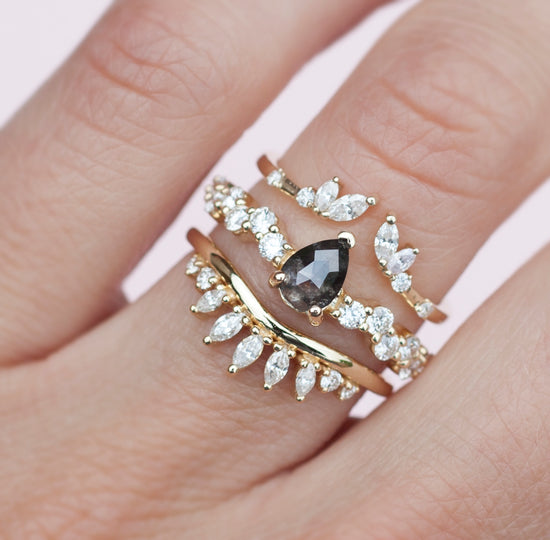 Salt and pepper diamond intertwine ring stacked on hand with two diamond bands.