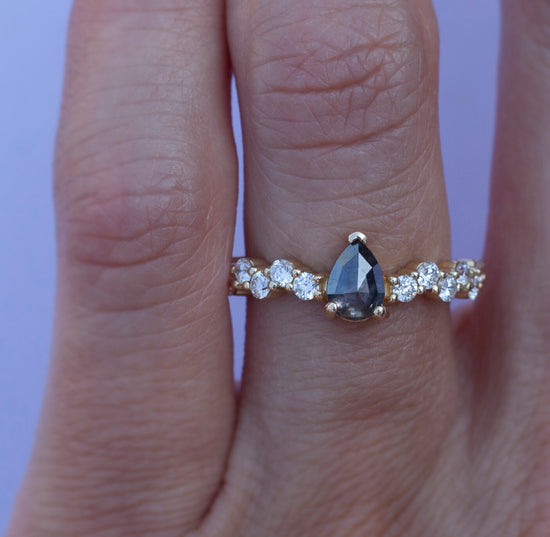 Load image into Gallery viewer, Salt and pepper pear shaped diamond set on a diamond cluster 14k gold band, on hand.
