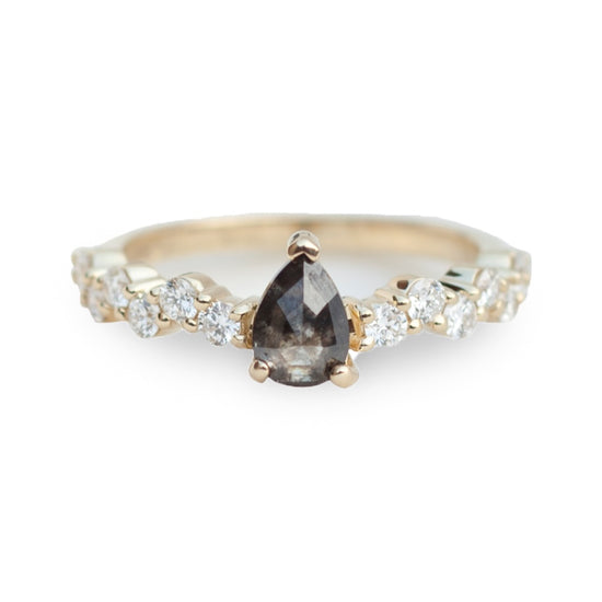 Salt and pepper pear shaped diamond set on a diamond cluster 14k gold band, on white background.