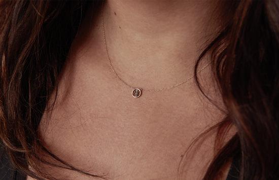 14k yellow gold, circle pendant with textural detail and baguette shaped diamond, on model.