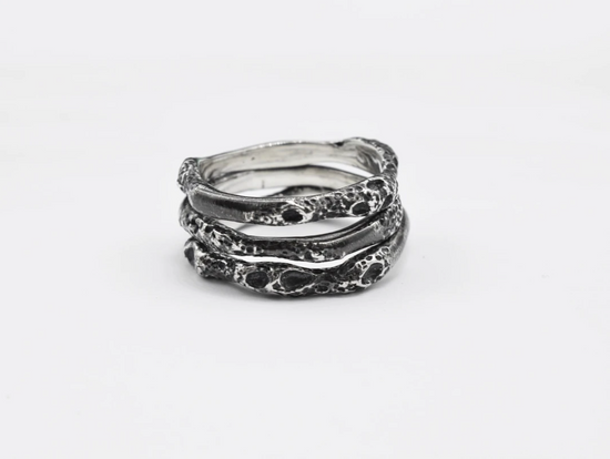 Three oxidized sterling silver rings stacked together on white background.
