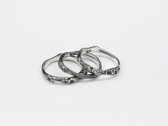 Three oxidized sterling silver rings layered on white background.