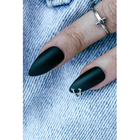 Hand modeling black press on nails with silver hoops attached.