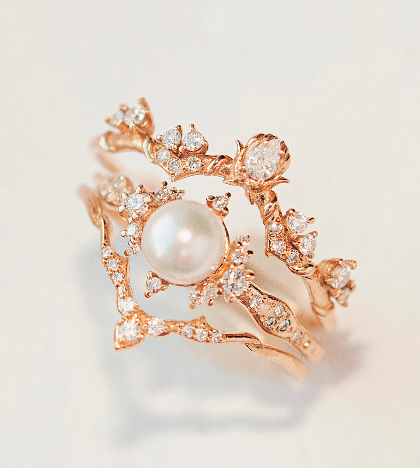 Pearl Birth of Venus Ring stacked with two diamond bands on white background.
