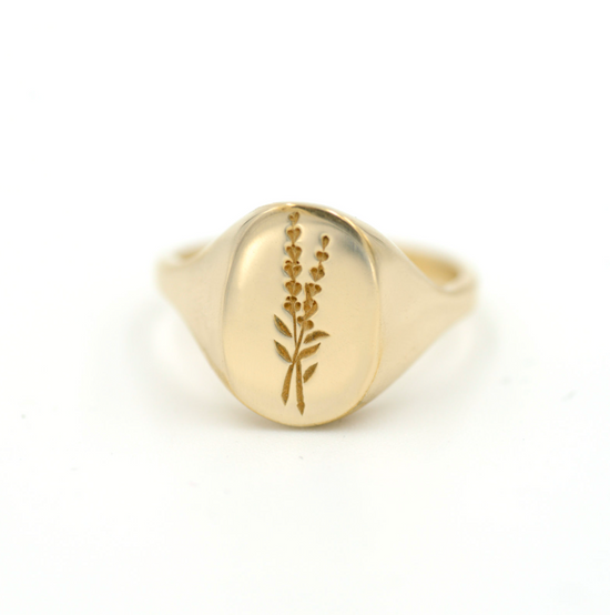 gold ring  with lavender flower detail in middle pictured on white background 