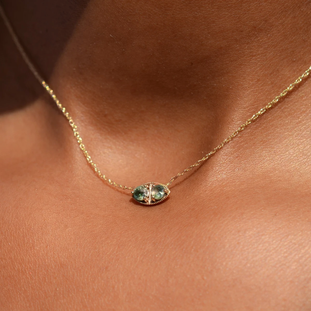close up of a model wearing the tiree necklace that has green gemstones