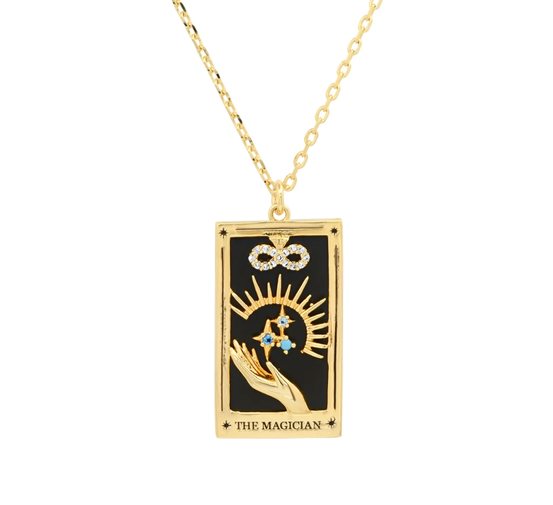 the magician tarot card pendant necklace featuring a black onyx background, gold hand holding crustal encrusted stars, a gold sunburst, and crystal encrusted infinity symbol.