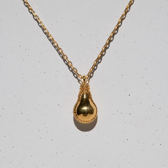 gold lightbulb shaped pendant on grey speckled background