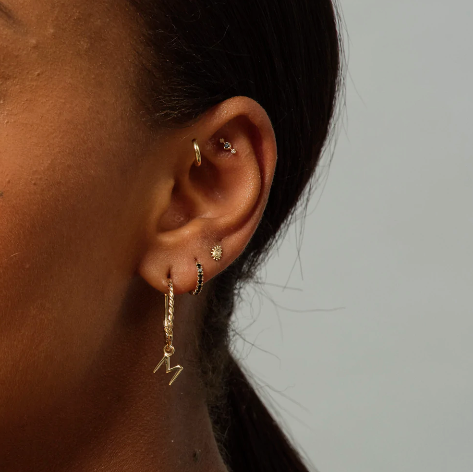 close up of a model wearing five gold and black diamond earrings