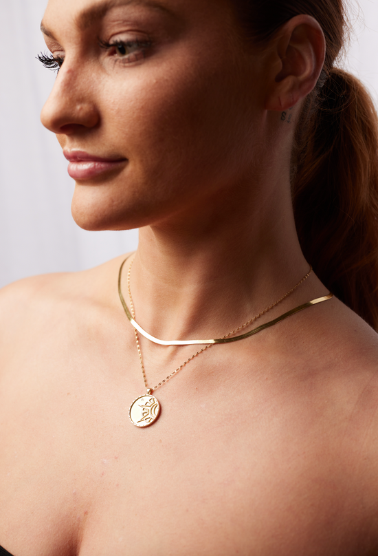 Load image into Gallery viewer, model wearing the gold herringbone chain necklace layered with a gold coin necklace
