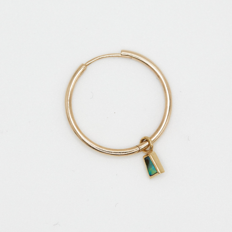 a gold hoop with baguette abalone charm on a light grey background