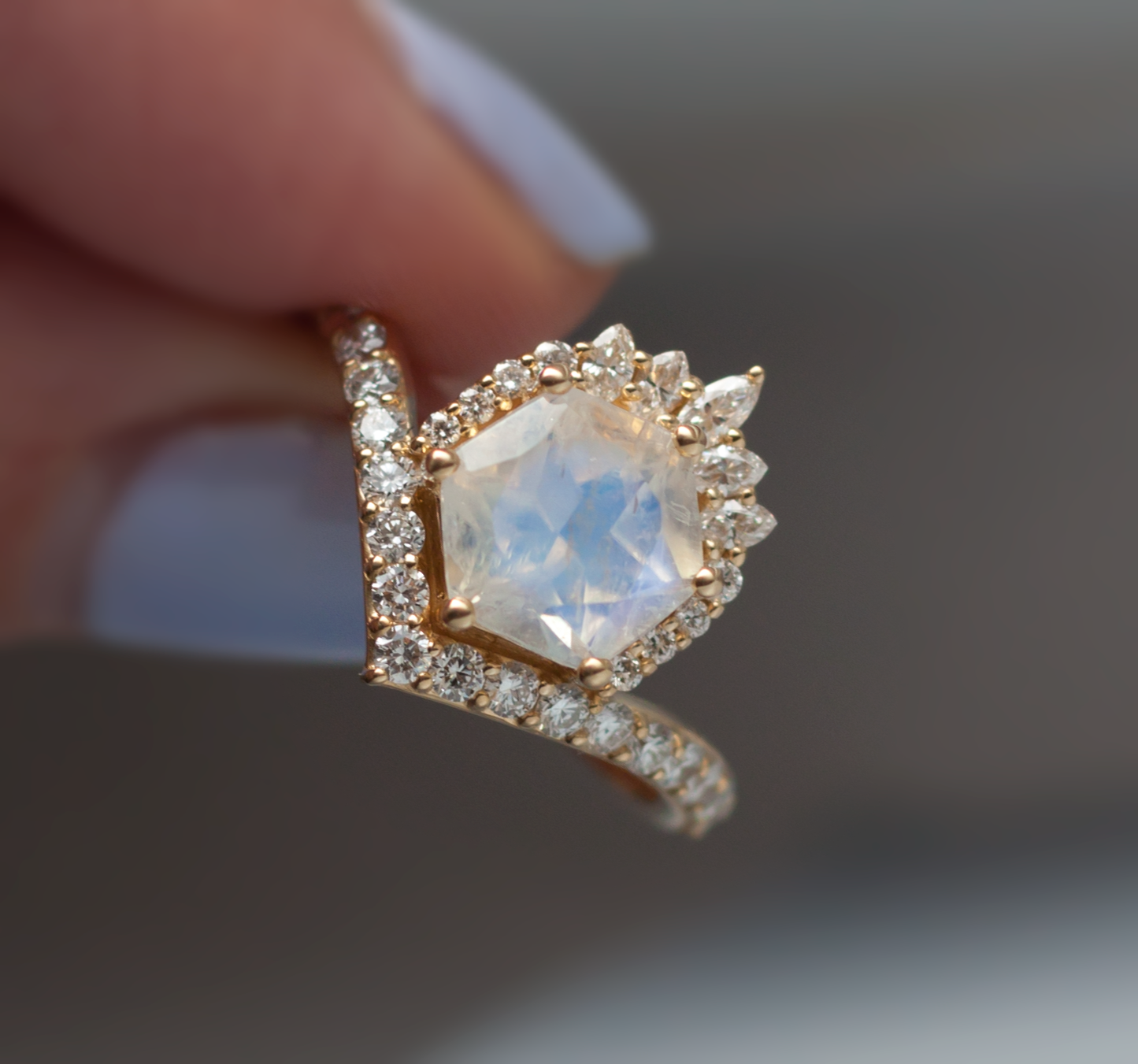 Hand holding the hexagon shaped moonstone devoir rings close up.
