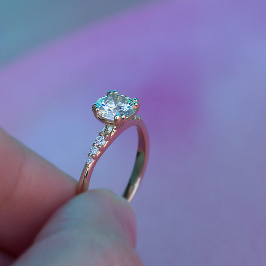 Load image into Gallery viewer, Side view of hand holding the diamond solitaire Rheia ring.
