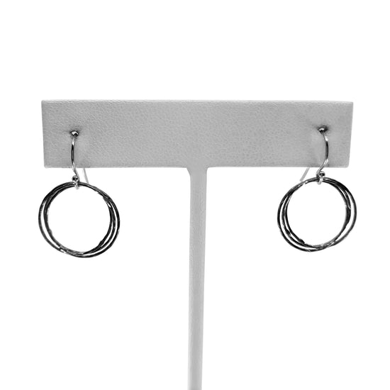 Oxidized and sterling silver triple circle earrings on earring stand with white background.