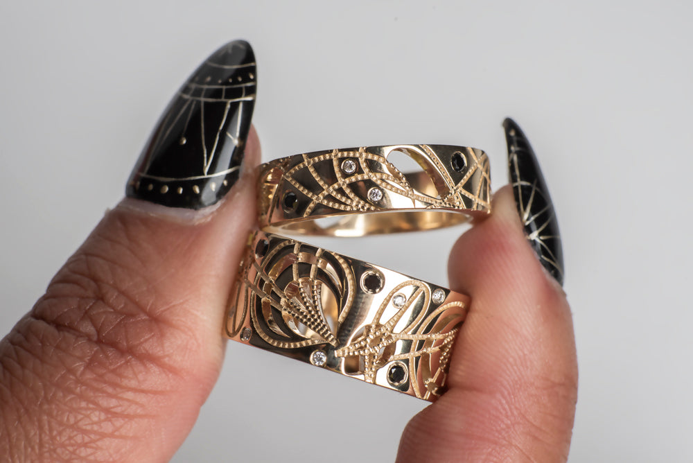 Load image into Gallery viewer, 2 yellow gold cigar bands with black and white diamonds, held by a model&amp;#39;s hand
