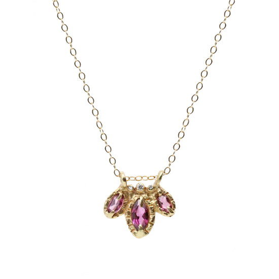 wider view of 3 purple marquis cut garnets, accompanied by diamonds, on gold chain pictured on white background